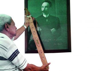 Javier muestra la Réplica del Machete Mambí del Generalísimo Máximo Gómez, junto a un cuadro de Martí