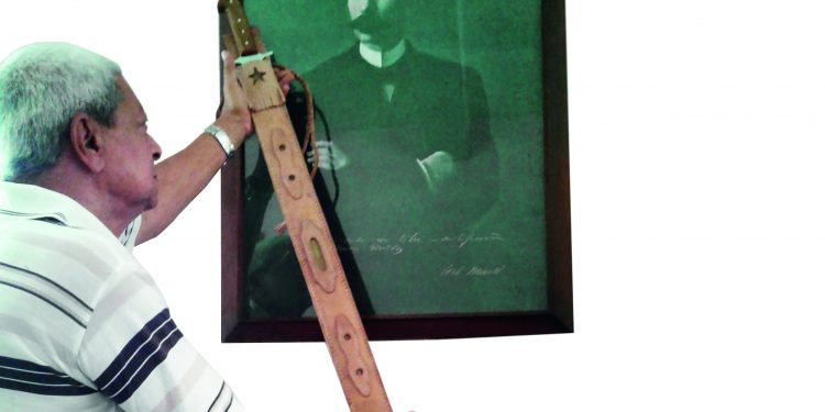 Javier muestra la Réplica del Machete Mambí del Generalísimo Máximo Gómez, junto a un cuadro de Martí