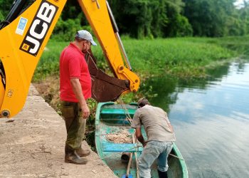 CON LA AYUDA de una retroexcavadora y un pequeño bote, transforman el paisaje del río