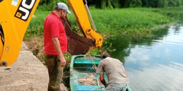 CON LA AYUDA de una retroexcavadora y un pequeño bote, transforman el paisaje del río